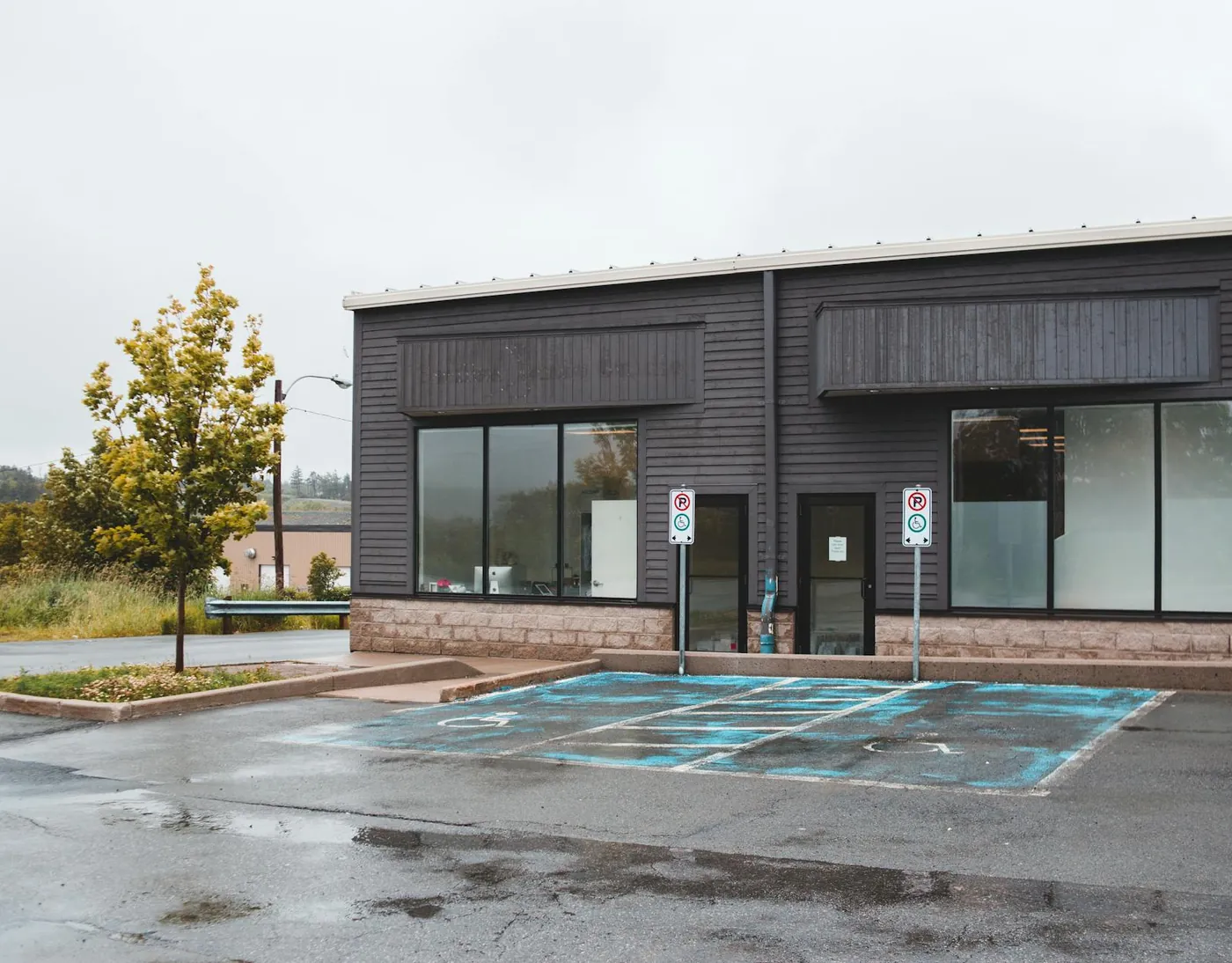 Dark-clad commercial building with glass storefront windows on an overcast day